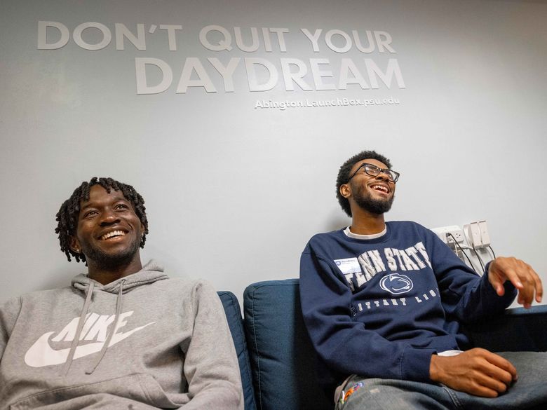 Two smiling students sit on a couch at 十大足彩平台’s LaunchBox space, with the words “Don’t quit your daydream” displayed on the wall behind them.